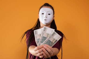 Anonim bir kadın, elinde yüz Polonyalı zloti değerinde kağıt banknotlarla elini uzatıyor. Yüzü yok çünkü üzerinde maske var..