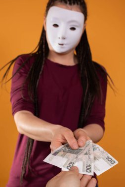 Bir erkek, isimsiz genç bir kadın tarafından verilen kağıt paralara uzanır. Katı turuncu renkte izole edilmiş bir figür.