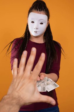 Bir erkek, isimsiz genç bir kadın tarafından verilen kağıt paralara uzanır. Katı turuncu renkte izole edilmiş bir figür.