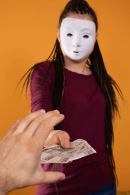 Bir erkek, isimsiz genç bir kadın tarafından verilen kağıt paralara uzanır. Katı turuncu renkte izole edilmiş bir figür.