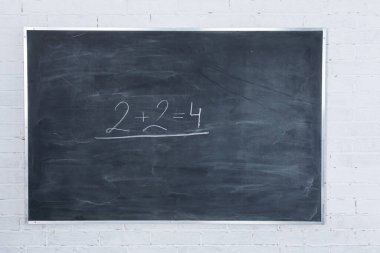 Tebeşir tahtası iyi süngerlenmemiş. Matematiğin en basit aritmetik problemi iki sayıyı bir araya getirmektir. Beyaz tuğla duvar.
