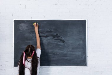 Ayakta duran bir genç, kirli bir okul tahtasını ıslak bir süngerle siliyor. Okul tahtası beyaz bir tuğla duvarda asılı. Yararlı bir kız tahtada duruyor..