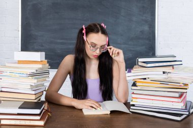 Sınıfta kitap yığınlarının arasında bir genç oturuyor ve ilk okumayı okumaya başlıyor. Öğrenci öğrenmeye başlar. Saçları iki at kuyruklu pembe bir kurdeleyle tutturulmuş..