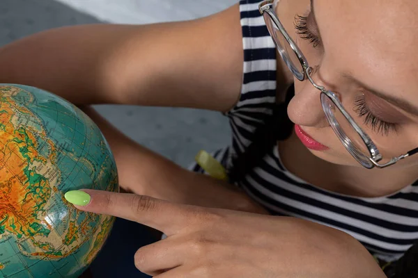 Dans le gros plan, vous pouvez voir une jeune fille malvoyante avec des lunettes regardant le globe de très près. Le meilleur élève à l'école. — Photo