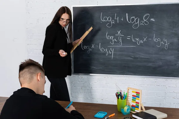 Вчитель математики пояснює тему та задачу з логарифмами студентам, які складають іспити матури цього року . — стокове фото