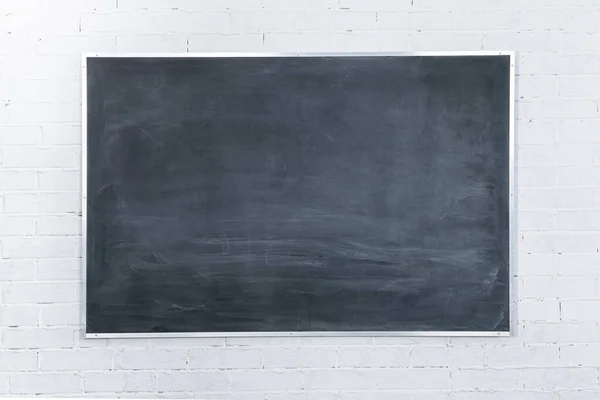 Chalkboard not well sponged. The simplest arithmetic problem in mathematics - adding two numbers together. White brick wall.