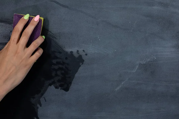 Une femme essuie à la main un tableau avec une éponge humide avant les prochaines leçons en classe. Prépare un endroit pour écrire sur un tableau noir d'école. — Photo