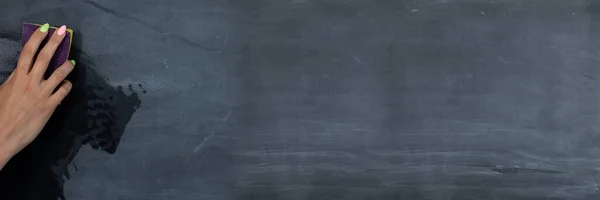 Cadre panoramique pour une femme essuyant à la main le tableau noir avec une éponge humide avant les prochaines leçons en classe. Prépare un endroit pour écrire sur un tableau noir d'école. — Photo