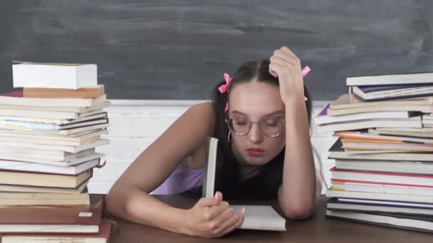 In der Schulbibliothek suchte sich der Teenager eines der vielen Bücher aus und begann es zu lesen. Gebundene lange dunkle Haare. Interesse am Lesen. — Stockvideo
