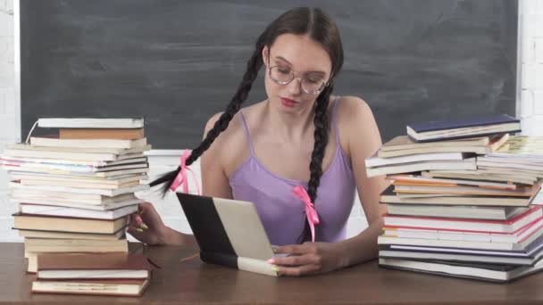 Di perpustakaan sekolah, remaja memilih salah satu dari banyak buku dan mulai membacanya. Berikat rambut hitam panjang. Tertarik dalam membaca. — Stok Video