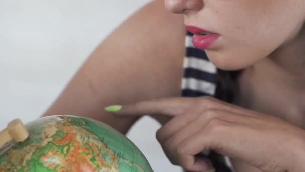 Een vrij close-up macro aardrijkskunde les met een wereldbol. Een tiener is op zoek naar een plek op de wereld die ze zou willen bezoeken. — Stockvideo