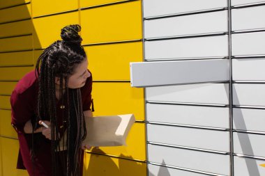 Paketi posta kutusundan çıkardıktan sonra, genç tek paket olup olmadığını kontrol eder. Kız posta kutusundaki tüm paketleri alıp almadığını kontrol ediyor..