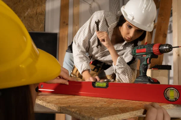 Las chicas comprueban con un nivel de espíritu si la superficie de la mesa en la que trabajan mantiene los parámetros de desviación aceptables del nivel. — Foto de Stock