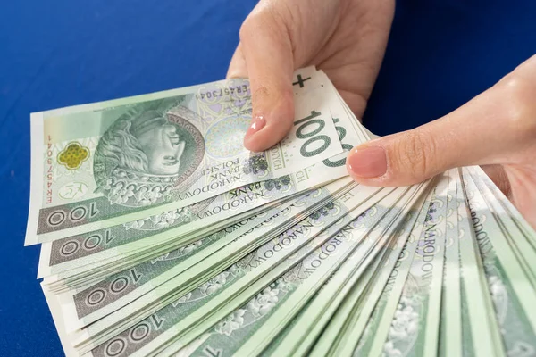 En sus manos tiene un abanico de billetes con un valor nominal de cien zlotys polacos. Muchos proyectos de ley para tener una opción. —  Fotos de Stock