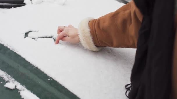На капоте пассажирского вагона лежит снег, и подросток пишет на нём слово "снег". Началась зима, отмеченная белым снегопадом. — стоковое видео