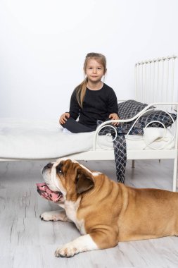 İngiliz Bulldog 'u, sadık koruyucusu tarafından küçük kızların yatağı tarafından korunuyor. Kız ve dört ayaklı evcil hayvanı.