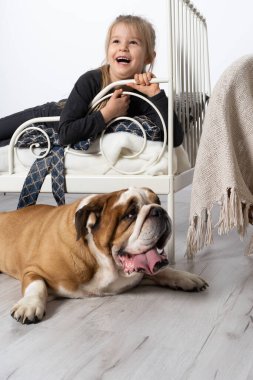 Kız yatağında yatıyor ve köpek sadakatle bekliyor ve yatağının yanında yerde yatıyor. Kız ve dört ayaklı evcil hayvanı.