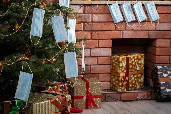 El árbol de Navidad está lleno de regalos que se desenvolverán el día de Navidad. Máscaras colgadas como adornos en el árbol de Navidad durante una pandemia en curso. — Foto de Stock