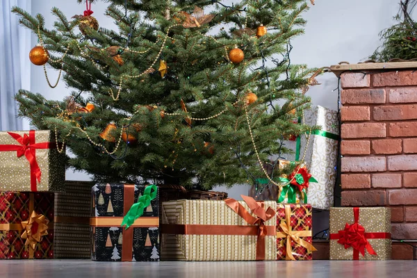 El árbol de Navidad está lleno de regalos que se desenvolverán el día de Navidad. Navidad tradicional. Una sala de estar cálidamente decorada en casa. — Foto de Stock