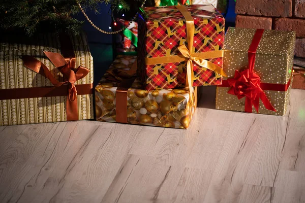 Hay muchos regalos bajo el árbol de Navidad que la familia y los amigos recibirán en Navidad. Navidad tradicional. Una sala de estar cálidamente decorada en casa. — Foto de Stock