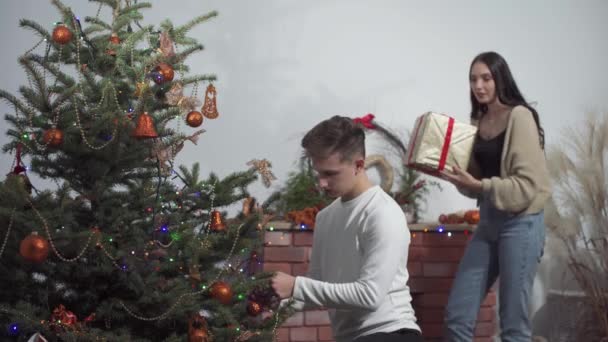 Beim Schmücken des Weihnachtsbaums beschloss die Verlobte, ihrem Freund ein Geschenk zu machen, um nicht bis Weihnachten zu warten.. — Stockvideo