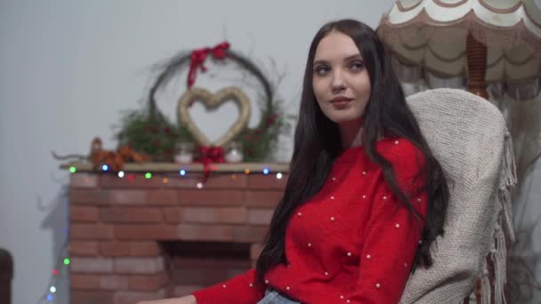 Dívka se houpe na křesle v obývacím pokoji doma a najednou její přítel přijde a dává dárek těsně před Vánocemi. — Stock video