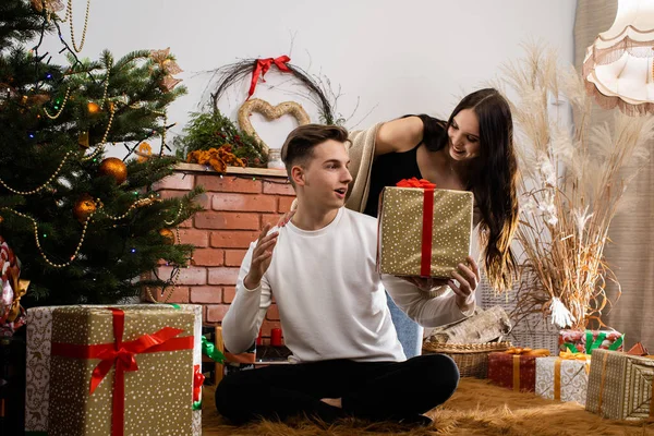 El prometido le da un regalo a su amante el día de Navidad. Un ambiente navideño único. Una sorpresa durante las vacaciones. — Foto de Stock