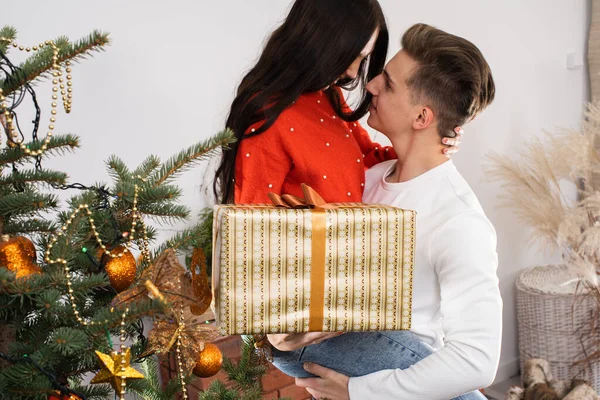 The boy lifted his beloved soybeans up for joy. A couple in love hug by the Christmas tree in their living room. A unique Christmas atmosphere.