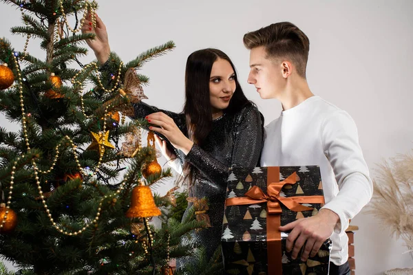 Justo antes de que comience la reunión, la novia y el novio están decorando el árbol de Navidad en casa para Navidad. Decoraciones navideñas. La chica y el chico trabajan juntos.. — Foto de Stock