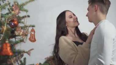 Noel için Noel ağacını süslerken, gelin ve damat sıcak bir sohbet ediyorlar. Genç bir kız ve genç bir oğlan..