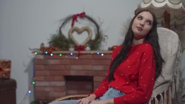 A menina está balançando na poltrona na sala de estar em casa e, de repente, seu namorado vem e dá um presente pouco antes do Natal. — Vídeo de Stock