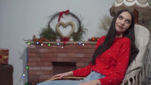 Das Mädchen schaukelt zu Hause auf dem Sessel im Wohnzimmer und plötzlich kommt ihr Freund und beschenkt sie kurz vor Weihnachten. — Stockvideo