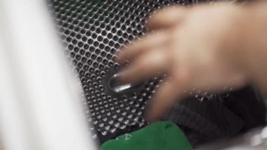 Çamaşır makinesinden çamaşır makinesinin üstü açık kıyafetlerin çıkarılması. Paslanmaz çelik davul.