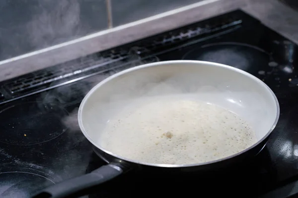 The pancake is placed in a hot pan and fried. The water in the pancake batter evaporates strongly due to high temperature. — Stock Photo, Image
