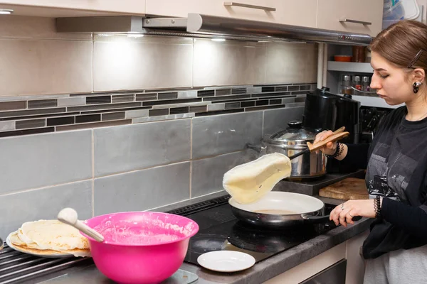 年轻的厨师用厨房里的锅子把煎饼转到另一边。自制煎饼. — 图库照片