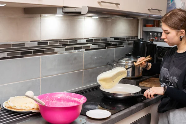 El joven cocinero gira el panqueque en la sartén hacia el otro lado usando la espátula de la cocina. Panqueques caseros. — Foto de Stock