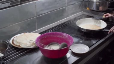 Genç bir delikanlı kızarmış krepi her iki yanında ocağın yanındaki bir tabağa taşır. Ev yapımı krep..