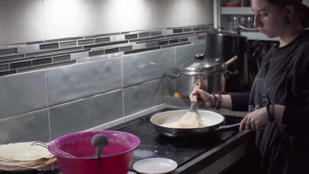 Młody nastolatek niesie gotowego smażonego naleśnika po obu stronach do talerza przy piecu. Domowe naleśniki. — Wideo stockowe
