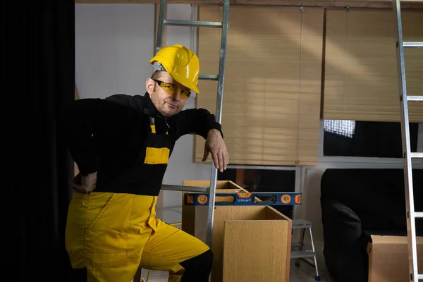 The builder checks with a spirit level that the cabinet is made correctly and without deviations. Construction worker wearing personal protective equipment. — Stock Photo, Image