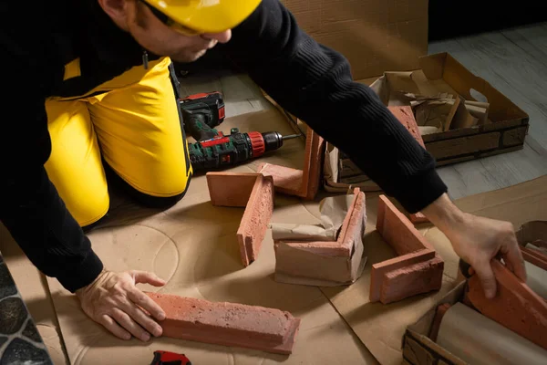 Der Bauarbeiter greift nach einer weiteren ziegelförmigen Zierplatte, um die geplanten Arbeiten fortzusetzen. Bauarbeiter trägt persönliche Schutzausrüstung. — Stockfoto