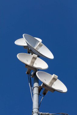 Bir hücresel ağın birkaç telekomünikasyon antenleri ve mavi gökyüzüne karşı kablosuz internet. Birden fazla bilgi parçası aynı anda alınıyor ve sayısallaştırılıyor.