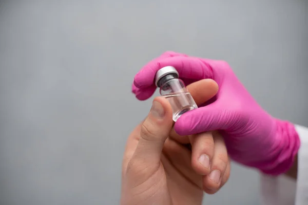 Le da un vial con un medicamento y una jeringa como conjunto completo para preparaciones inyectables, incluyendo vacunas contra la gripe y virus COVID19. Un consultorio médico estéril en una clínica privada. Vista de primer plano. — Foto de Stock