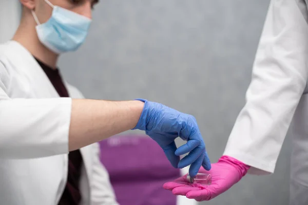 Doktor stajyere içinde grip ve COVID19 aşıları da dahil olmak üzere enjeksiyon seti olarak bir ilaç ve şırınga veriyor. Özel bir klinikte steril bir doktor ofisi.. — Stok fotoğraf