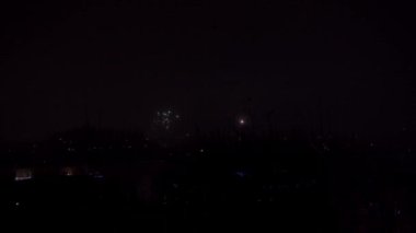 Yeni yılı kutladığımız gün, Lublin 'in panoramasının üzerinde havai fişekler. Periyodik olarak alevlerin ve diğer havai fişeklerin parlak ışıkları karanlık arka planda parlıyor. Kutlama ve binlik