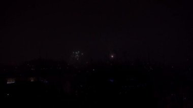 Yeni yılı kutladığımız gün, Lublin 'in panoramasının üzerinde havai fişekler. Periyodik olarak alevlerin ve diğer havai fişeklerin parlak ışıkları karanlık arka planda parlıyor. Kutlama ve binlik