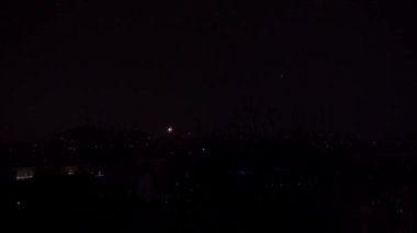 Yeni yıl kutlamaları sırasında dar bir çerçeve. Periyodik olarak alevlerden ve diğer havai fişeklerden gelen parlak ışıklar koyu arkaplana çarpıyor.