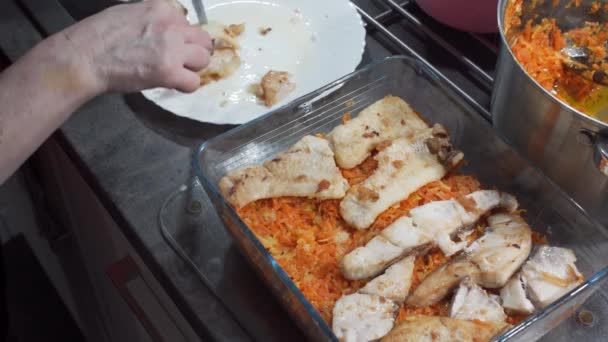 Het regelen van gebakken stukjes vis op gekookte gehakte groenten tot een gerecht genaamd vis in het Grieks te vormen. Dikke stukken kabeljauw. Thuis koken. — Stockvideo