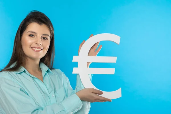 Dziewczyna trzyma w rękach duży symbol euro. Kształt waluty Unii Europejskiej. Symbol finansów i przepływów pieniężnych w gospodarce i na giełdzie na solidnym tle. — Zdjęcie stockowe