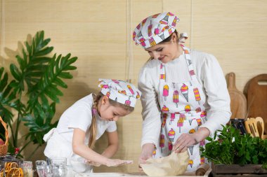 Anne ve kızı birlikte pastayı fırlatıp, elleriyle okşayacaklar. Anne ve bebek mutfakta hamuru birlikte yapıyorlar..