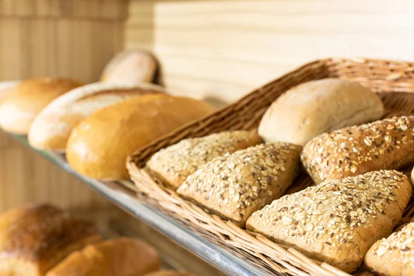 A freshly baked triangular-shaped bun with various seeds is on the shelf of a bakery store. — Stock Photo, Image